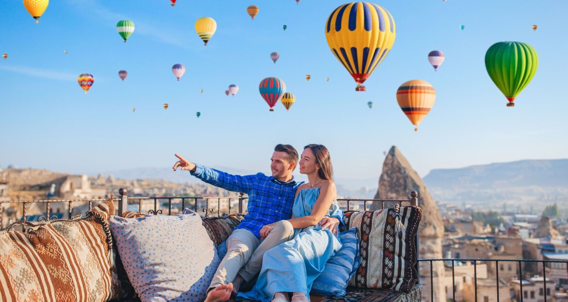 Happy young couple having fun an their honeymoon during sunrise watching hot air balloons in Cappadocia, Turkey